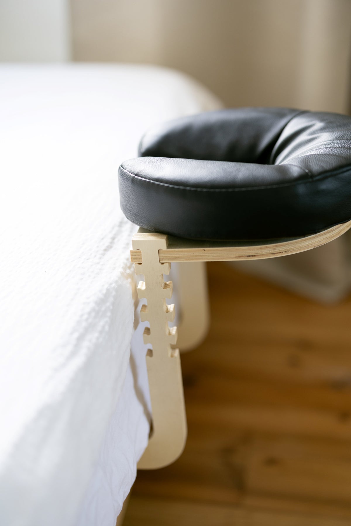 Het zwarte hoofdkussen op het houten frame aan de rand van een opgemaakt bed