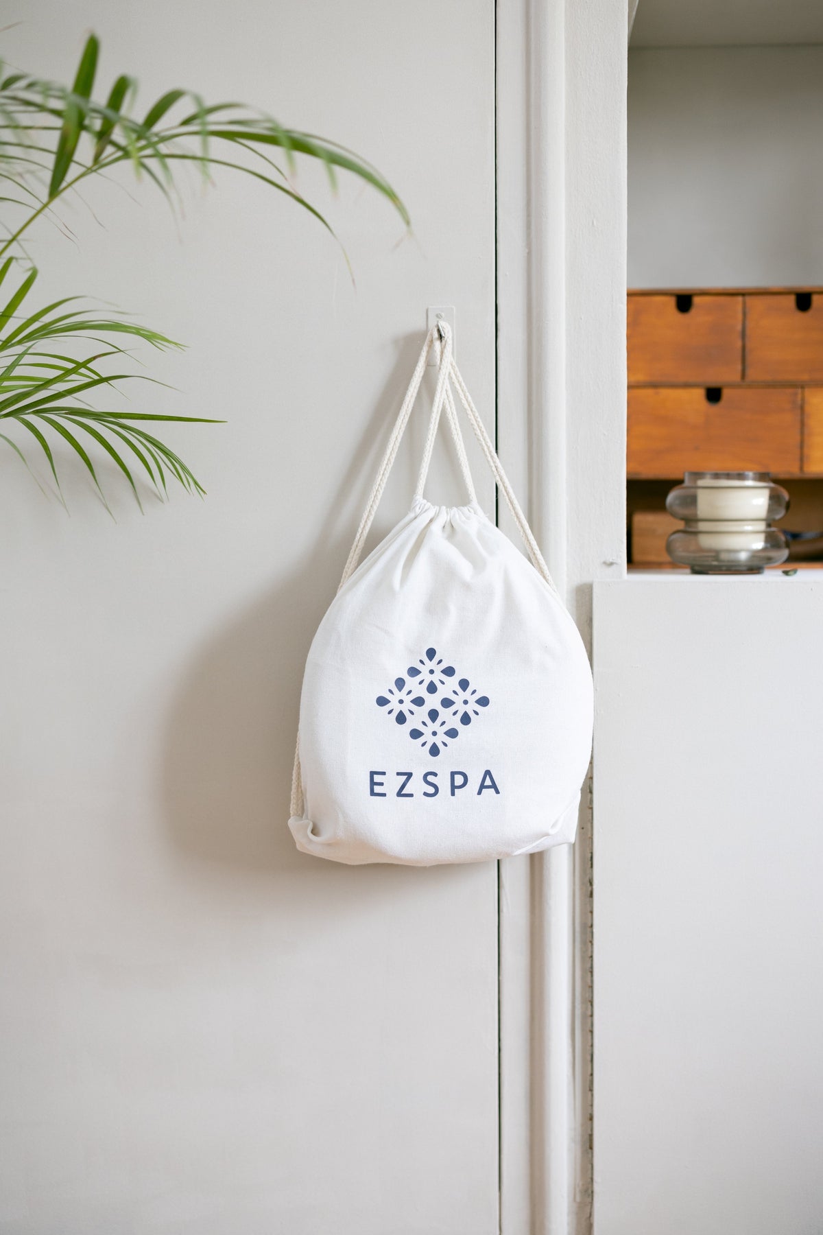 De katoenen draagtas van Ezspa met het logo, opgehangen in een slaapkamer