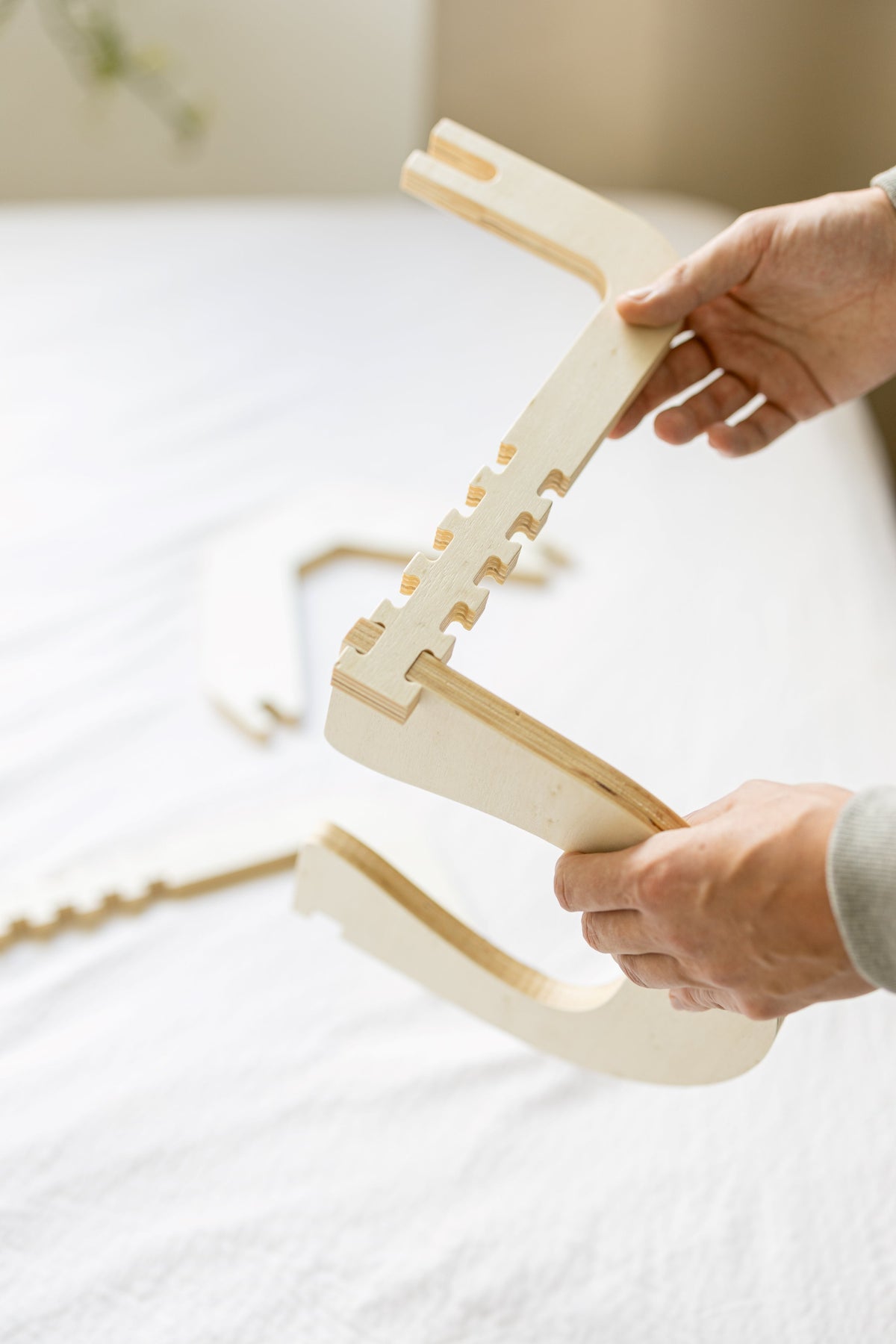Twee handen klappen het houten frame van de Ezspa Bedmassage Set open