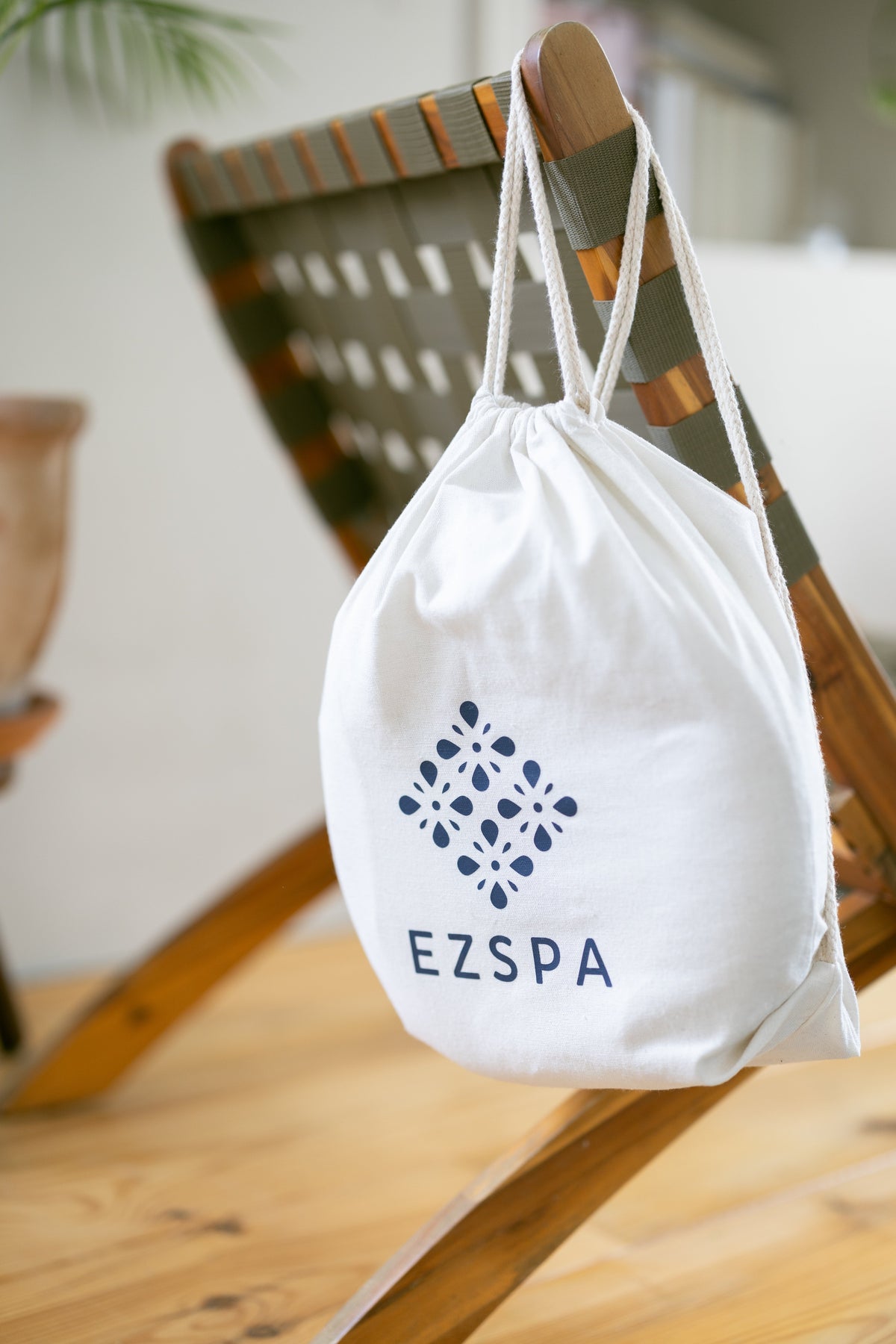 De katoenen draagtas van Ezspa met het logo, hangend aan een stoel