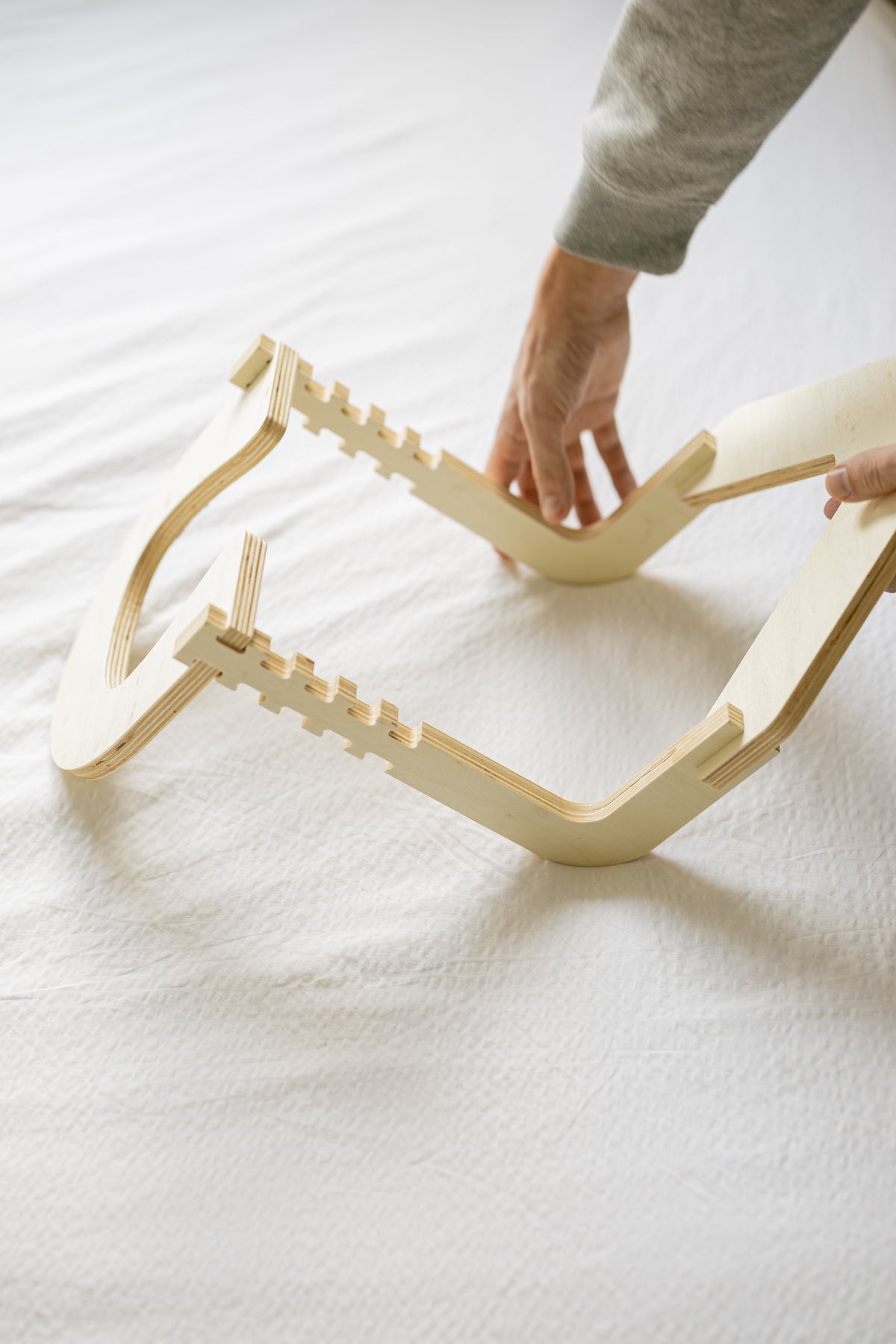 Handen zetten het houten frame in elkaar op een opgemaakt bed