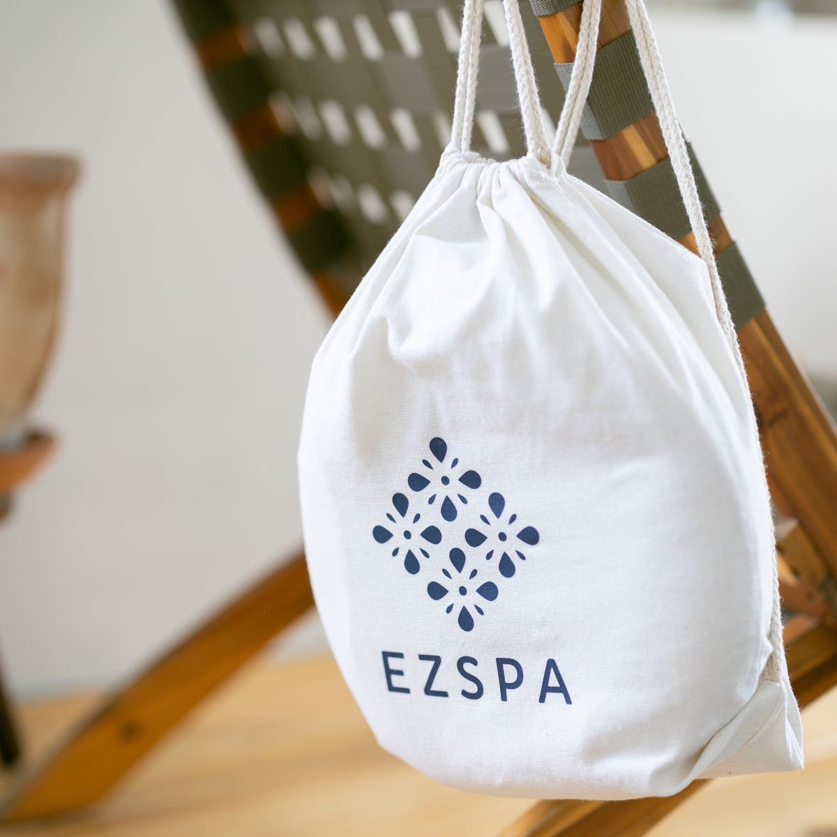 De katoenen draagtas van Ezspa met het logo, hangend aan een stoel