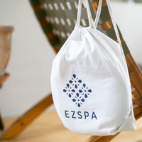 De katoenen draagtas van Ezspa met het logo, hangend aan een stoel