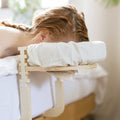 Vrouw ligt op bed met haar gezicht in de hoofdsteun van de Ezspa Bedmassage Set